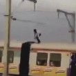 In piedi sul treno in corsa, si abbassa per evitare i tralicci