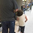 Lega capelli figlia al carrello e la trascina per il supermercato 01