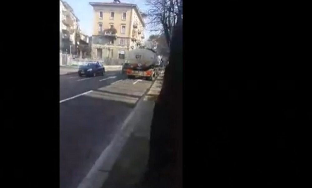 Nel video si vede un uomo appollaiato sulla fiancata di un camion in movimento.