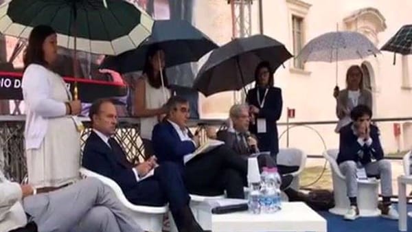 Piove al convegno, "volontarie" reggi-ombrelli per i relatori: la foto delle polemiche