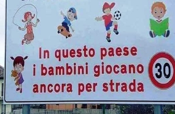 Il cartello stradale: "In questo paese i bambini giocano ancora per strada" (foto Ansa)