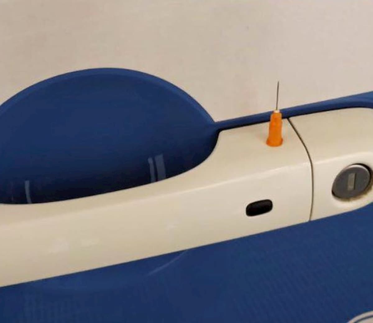 L'ago della siringa infilato nella maniglia della portiera della voltante