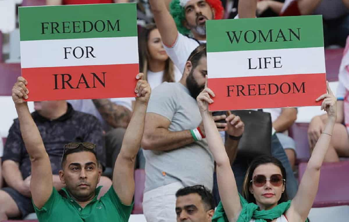 Iran, i calciatori non cantano l'inno. I tifosi li insultano. Ma dalla tribuna anche cartelli a favore dei manifestanti