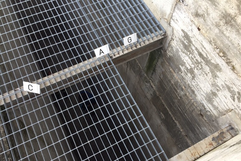 Cammina per strada e precipita in una grata aperta addosso a un operaio